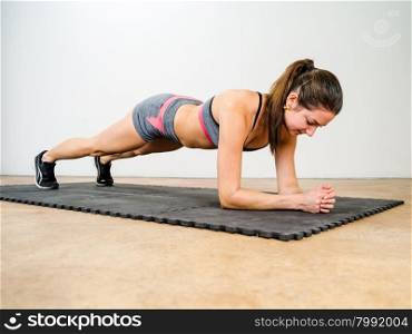 Photo of a beautiful young woman exercising and doing an elbow plank to strengthen her stomach muscles.