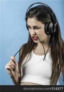 Photo of a beautiful young woman having fun listening to music with large headphones.