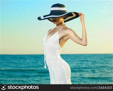 Photo of a beautiful young woman in a hat by the sea