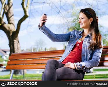 Photo of a beautiful young woman using a smartphone to take a selfie.