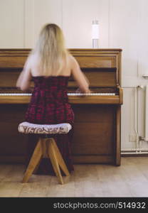 Photo of a blond woman in her early thirties playing the piano at home. Plenty of motion blur visible.