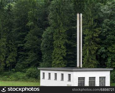 Photo of a factory building sitting in front of a huge forest background.
