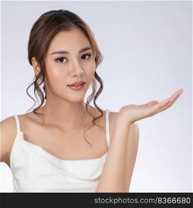 Photo of a gorgeous woman with flawless healthy fresh skin in a concept of empty space for beauty care product. Skincare product, model uses hand to create empty space for commercial.. Gorgeous woman with healthy skin in a concept of empty space for beauty product.