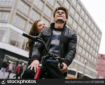 Photo of a happy couple in love outdoors during autumn riding a bicycle. Shallow depth of field with focus on the man. Photo is from the PhotoWalk in Berlin during Microstock Expo.