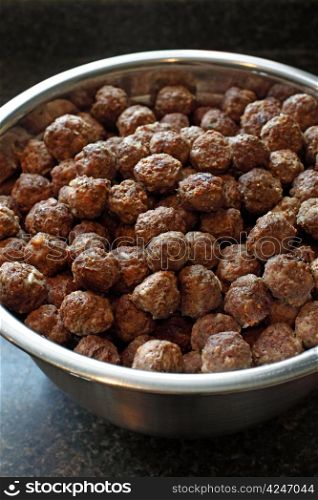 Photo of a huge bowl of beef meatballs in a commercial kitchen. Shallow depth of field.