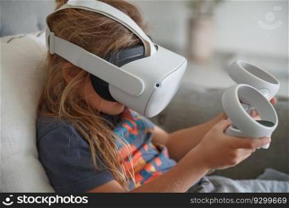 Photo of a little boy wearing VR mask playing video game at home. Modern technology. Simulation of a virtual reality. Smart child enjoying cyberspace.. Little boy playing video game at home