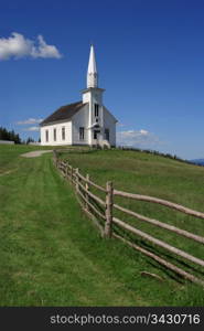 Photo of a little white wooden church in the countryside.