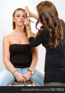 Photo of a makeup artist applying eye makeup onto a blond model.&#xA;