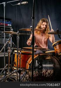 Photo of a male drummer playing his drum set at a recording studio.