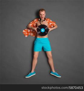 Photo of a male fashionable handsome hipster, wearing vintage music headphones around his neck and holding an LP microgroove vinyl record on dark background.