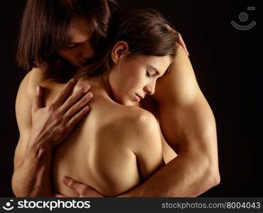 Photo of a man and woman in love and holding each other over a dark background.