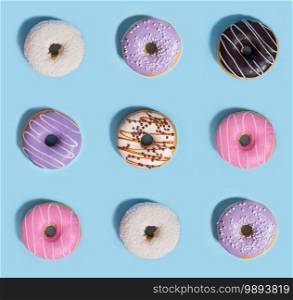 Photo of a nine colorful sweeties donuts over blue table background.. Nine colorful sweeties donuts