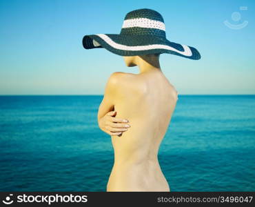 Photo of a nude beautiful woman in a hat by the sea