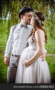 Photo of a pregnant bride and groom kissing during the wedding ceremony.