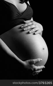 Photo of a pregnant female with her hands on her belly done in black and white