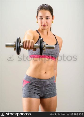 Photo of a pretty woman doing shoulder exercises with a dumbbell.&#xA;
