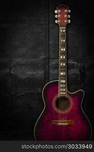 Photo of a purple acoustic guitar leaning up against a dark metal background.. Purple acoustic guitar over dark background