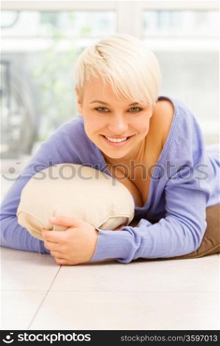 Photo of a smiling woman with short hairs laying on a pilow