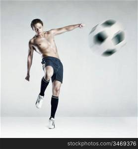 Photo of a strong topless athlete kicking the ball