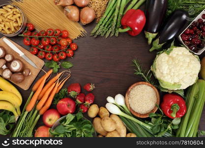 Photo of a table top full of fresh vegetables, fruit, and other healthy foods with a space in the middle for text.