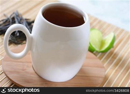 Photo of a tea mug with a wooden saucer and a lemon