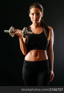 Photo of a toned young female exercising with a dumbbell over a dark background.&#xA;