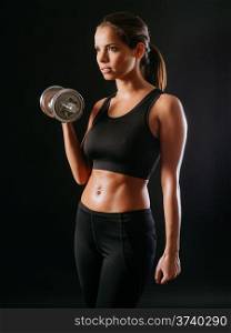 Photo of a toned young female exercising with dumbbells.