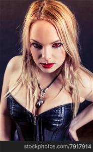 Photo of a woman with red eyes and red lipstick wearing a black leather corset. Harsh lighting and filtered for scarier feel.
