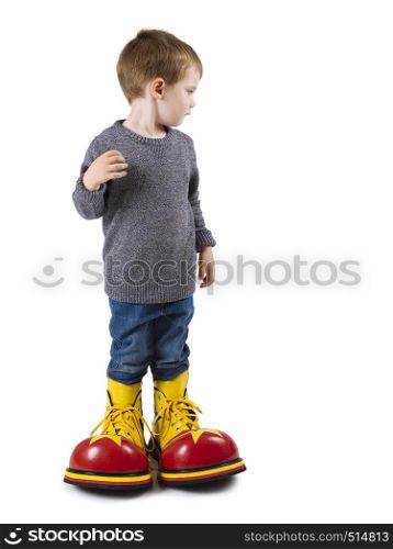 Photo of a young boy wearing huge clown shoes.