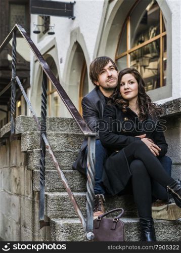 Photo of a young couple sitting and resting in an old town in Europe.&#xA;