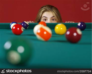 Photo of a young girl checking the billiard balls for a chance at a good shot.