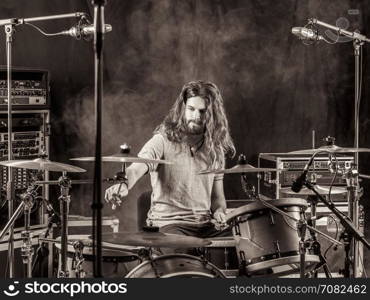 Photo of a young male drummer with long hair playing his drum set.&#xA;