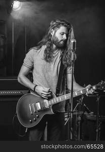 Photo of a young man playing electric guitar on stage.