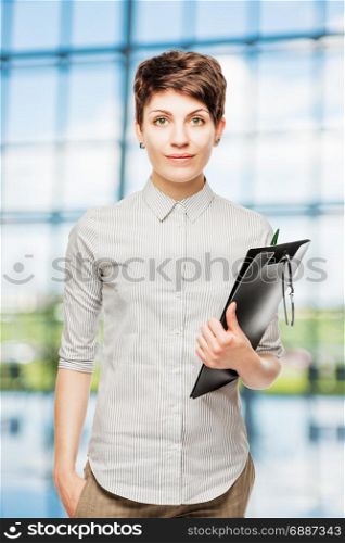 photo of a young slim businesswoman in the office, holding a folder