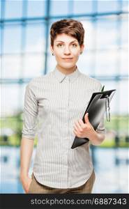 photo of a young slim businesswoman in the office, holding a folder