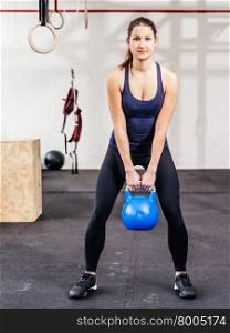 Photo of a young woman exercising with a kettle bell at a crossfit gym. &#xA;