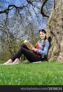 Photo of a young woman student studying outside under a tree.