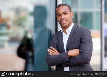 photo of african smiling businessman standing next to the glass wall