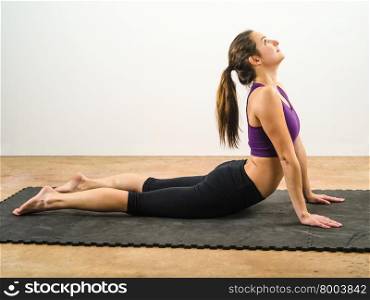 Photo of an attractive female in her 20&apos;s doing yoga stomach stretches.