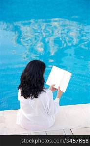 photo of an attractive lady reading ia book in the swimming pool
