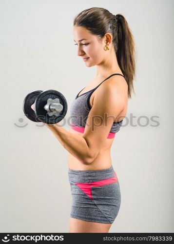 Photo of an attractive woman doing a dumbbell curl while standing.&#xA;