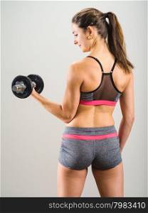 Photo of an attractive woman doing a dumbbell curl while standing.&#xA;