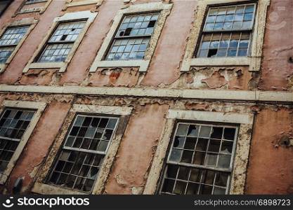 Photo of an old broken building exterior with busted windows and peeling paint.