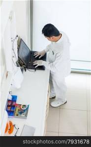 photo of asian dentist working on a computer in his office