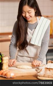 photo of asian smiling woman baking bread in her home kitchen