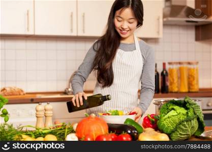 Photo of asian smiling woman pouring olive oil into the colorful salad