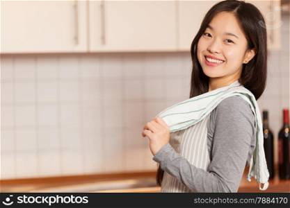photo of asian smiling woman standing with a towel on his shoulder in the kitchen
