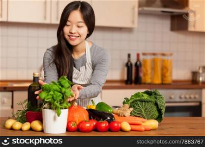 photo of asian young woman standing in the kitchen with colorful ingredients on the table