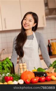photo of asian young woman standing in the kitchen with colorful ingredients on the table