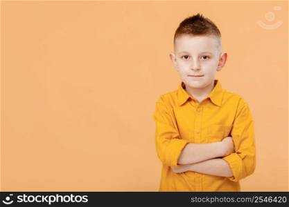 Photo of attractive cheerful nice school boy standing with his arms crossed in front of camera while isolated on yellow background. High quality photo.. Photo of attractive cheerful nice school boy standing with his arms crossed in front of camera while isolated on yellow background. High quality photo